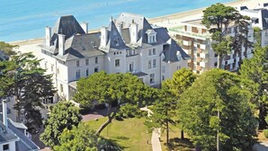 A coastal hotel with a large building, a beach, and a view of the sea. - Hôtel Vacances Bleues Villa Caroline (La Baule-Escoublac)