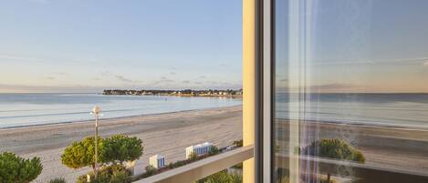 Une vue depuis un balcon donnant sur une plage, avec un ciel dégagé.