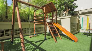 Children can play on the climbing structure, slide, and swing set in this outdoor play area.