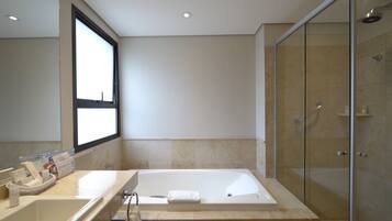 A modern bathroom with a large bathtub, a glass shower enclosure, and a window providing natural light.