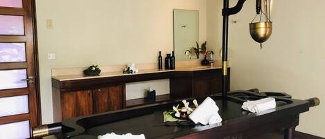A billiards table in a room with a wooden floor, a wooden door, and a mirror above a sink.