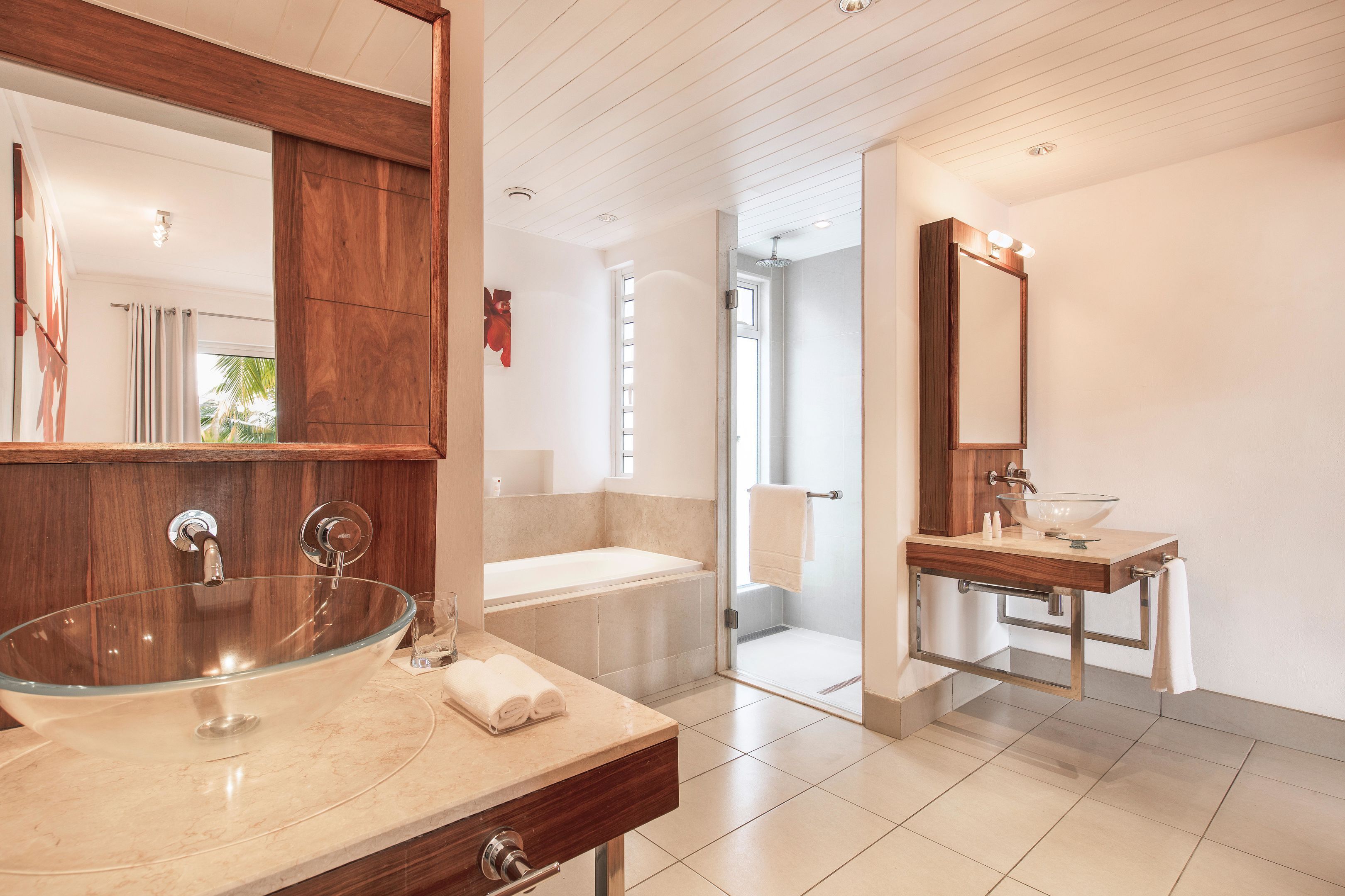 Un bany modern amb un lavabo de vidre, un moble de tocador independent, una banyera i una platja de dutxa.