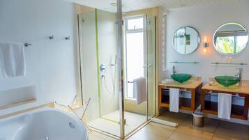Une salle de bain moderne dotée d’une douche à parois de verre, d’une baignoire sur pieds et de deux vasques avec des cuves vertes.