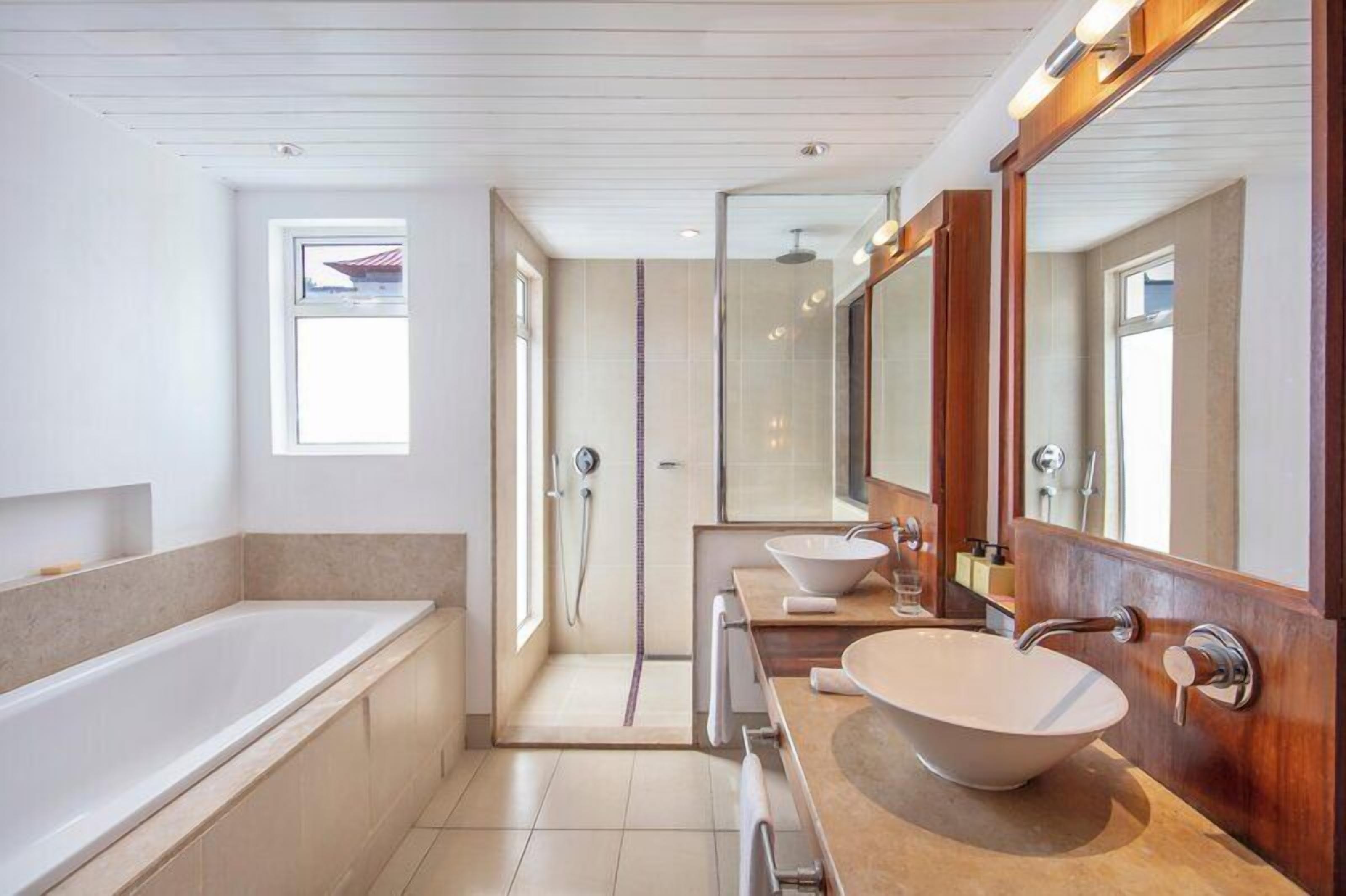 A modern bathroom with a bathtub, a large mirror, and a vanity with a sink.