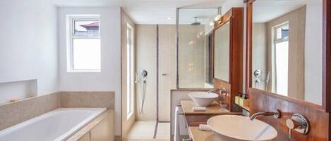 Un baño moderno con bañera, un espejo grande y un tocador con lavamanos.