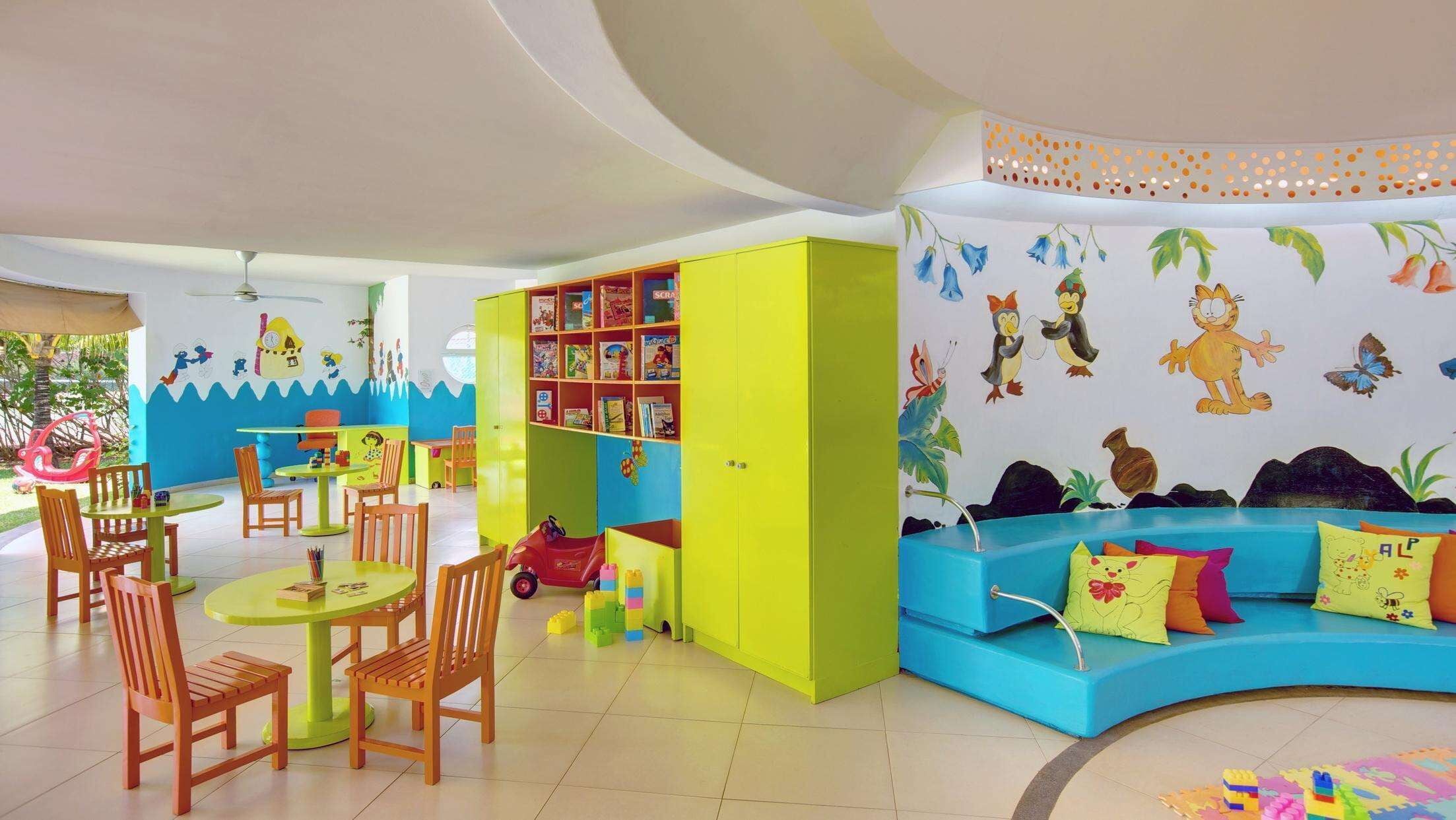 Een speelruimte voor kinderen met kleurrijk meubilair, een boekenplank en vrolijke wanddecoraties.