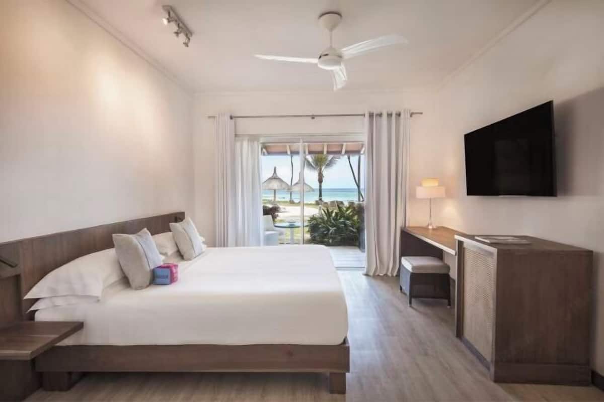 Une chambre d’hôtel avec un lit, un bureau, une télévision et une vue sur l’océan.