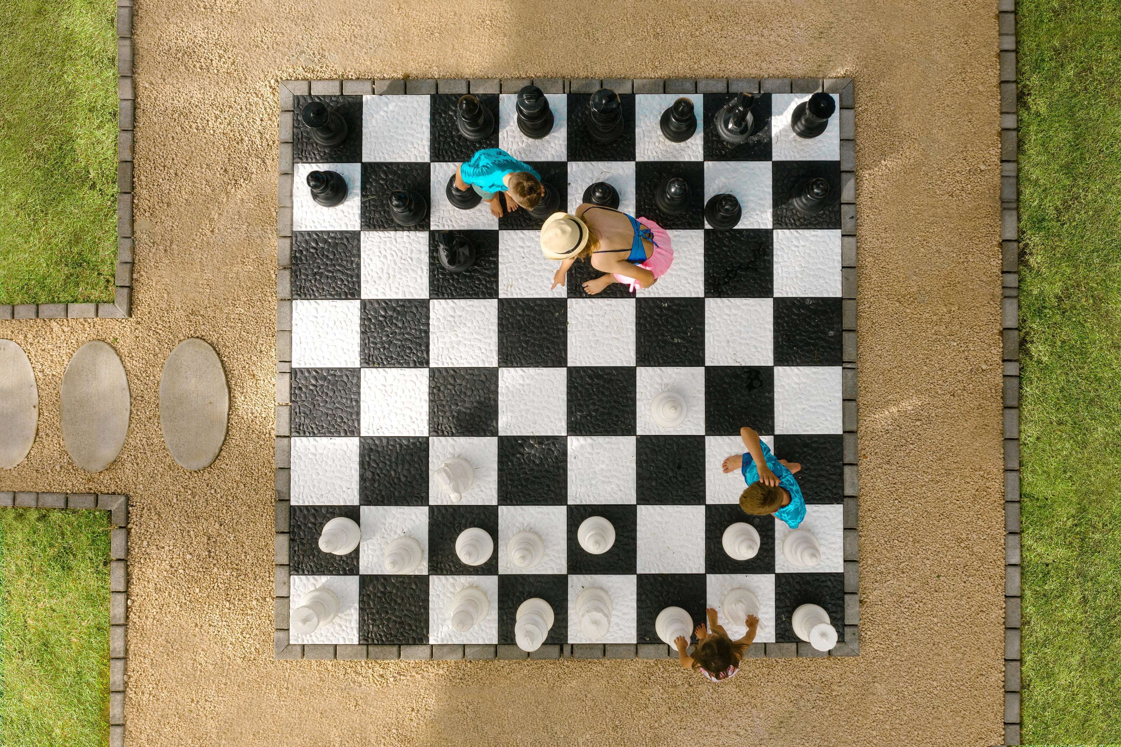 A checkered outdoor area with a paved path and a small pool.