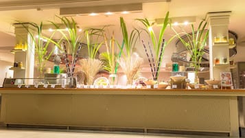 A reception area with a counter, potted plants, and shelves with jars.