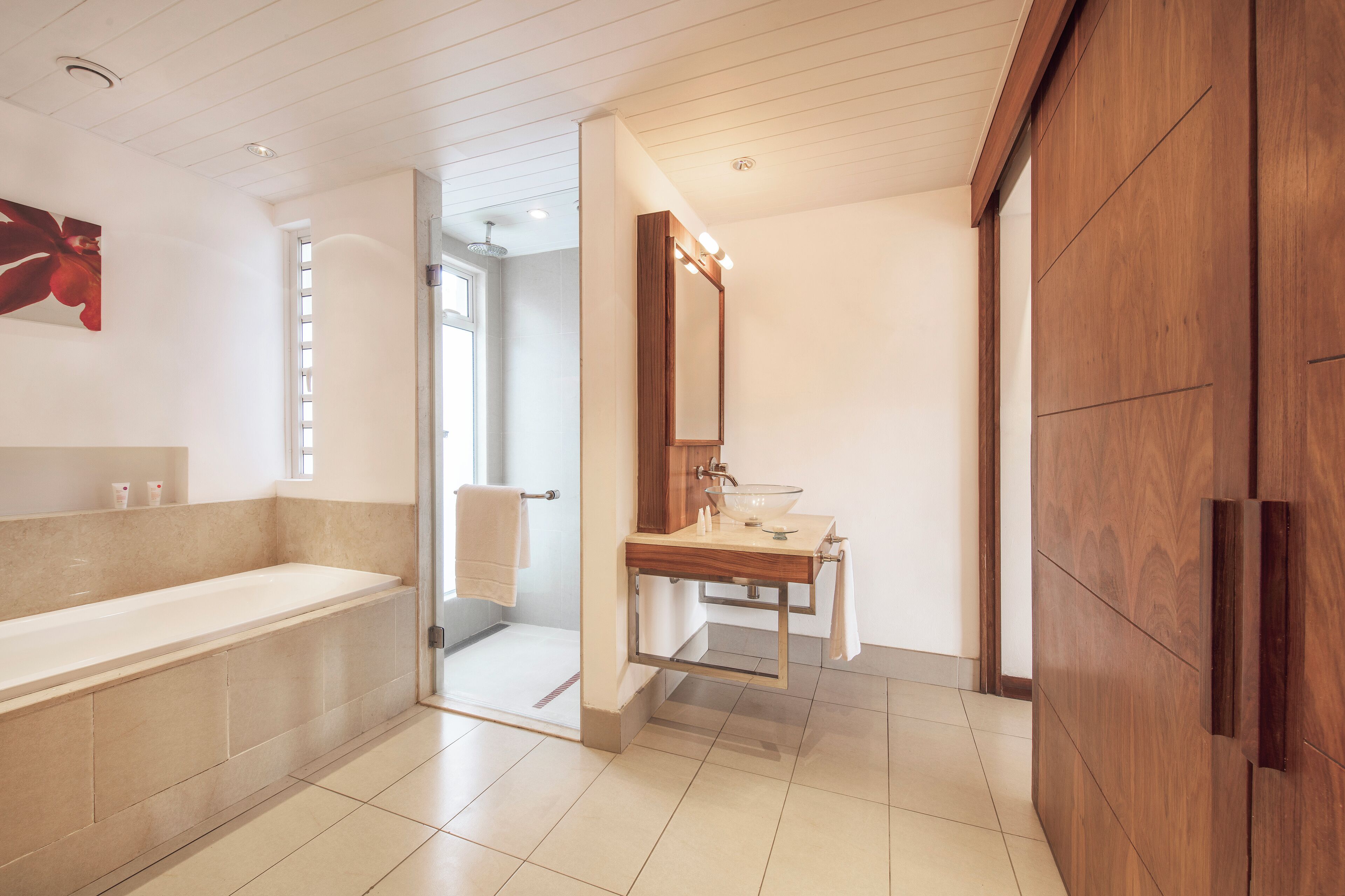 A modern bathroom with a large bathtub, a wooden vanity, and a mirror.