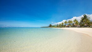 Una playa con agua turquesa cristalina, arena blanca y palmeras.