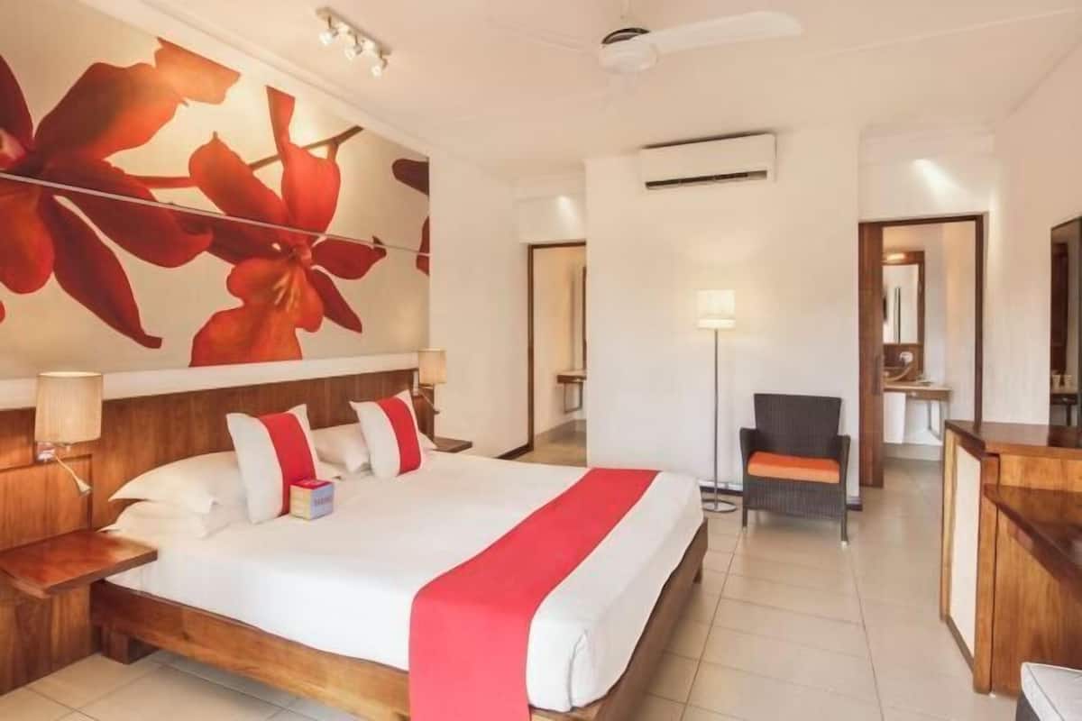 Une chambre d’hôtel avec un grand lit, un bureau, une chaise et un mur orné d’un motif floral.