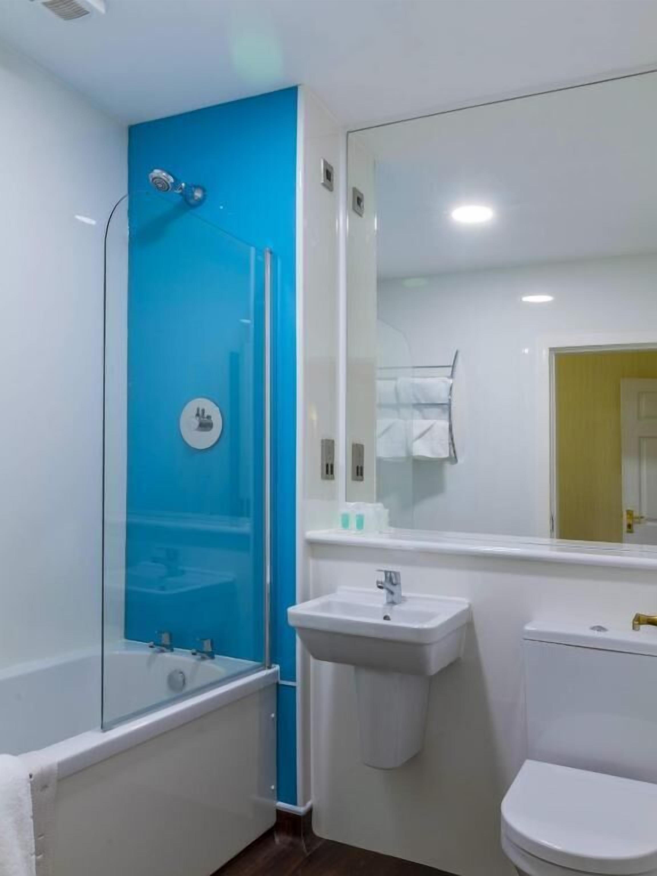 A modern bathroom with a glass-enclosed shower, a white sink, and a toilet.
