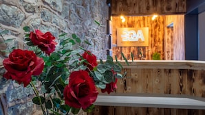 A reception area with a stone wall and wooden paneling, featuring a sign for '32A Restaurant Bar'.