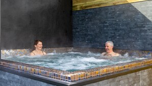 A hot tub with tiled walls and a wooden ceiling.