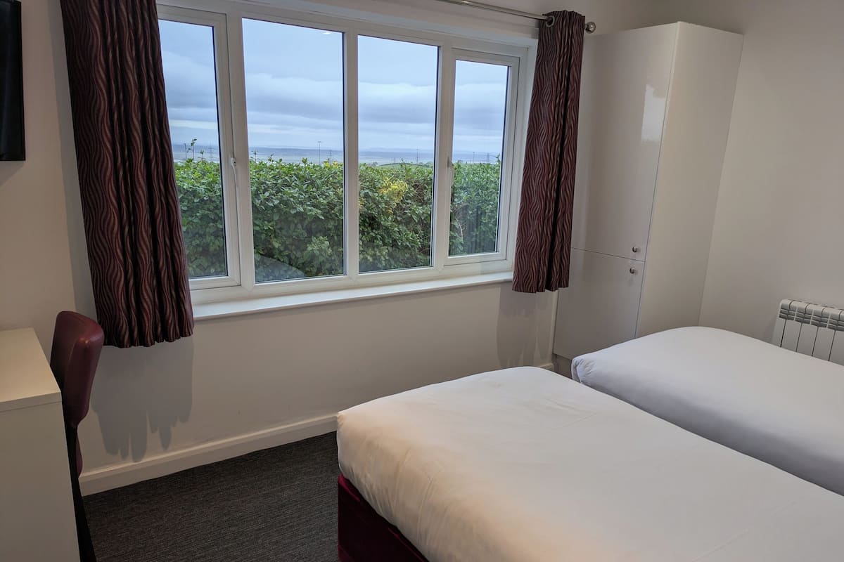 Habitación de hotel con un ventanal grande, una cama, un armario y un escritorio.
