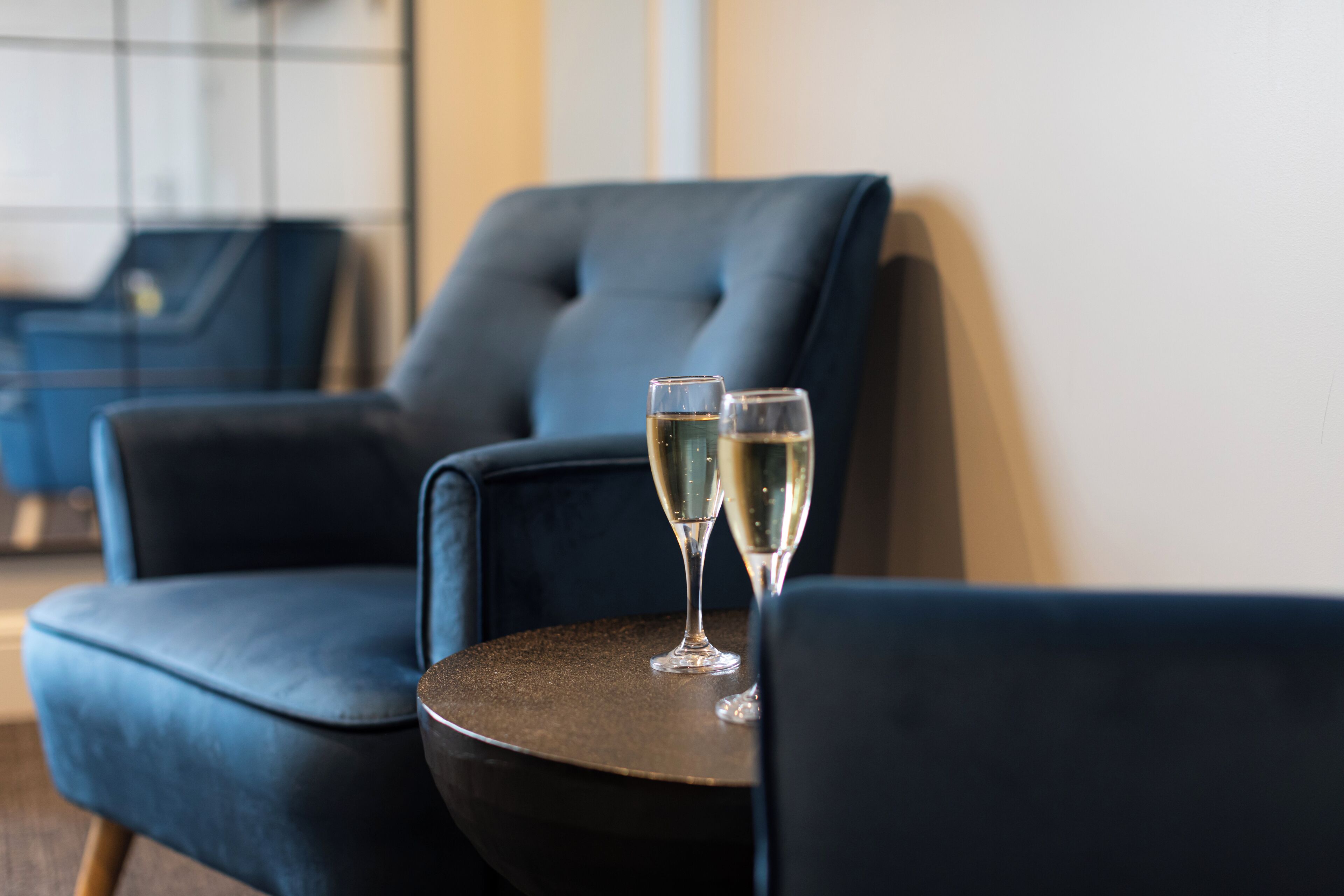 Ein dunkelblauer Sessel und ein kleiner runder Tisch mit zwei Champagnergläsern.