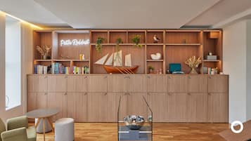 Un salon moderne avec un meuble en bois, des étagères, un panneau lumineux néon, des objets décoratifs et une petite table.