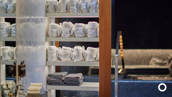 Un vestíbulo de hotel con estantes que exhiben toallas dobladas con orden en tonos blanco y gris.
