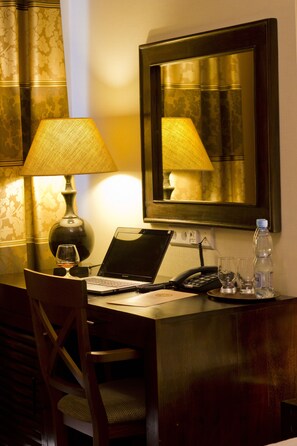 A hotel room with a desk, laptop, lamp, chair, and a mirror. - Columbus Hotel (Kraków)