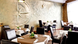 Un restaurante con mesas redondas, sillas y una gran rueda decorativa en la pared.