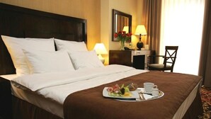 Una habitación de hotel con una cama bien hecha, una bandeja de desayuno con comida y bebidas, un escritorio con una lámpara y una silla.
