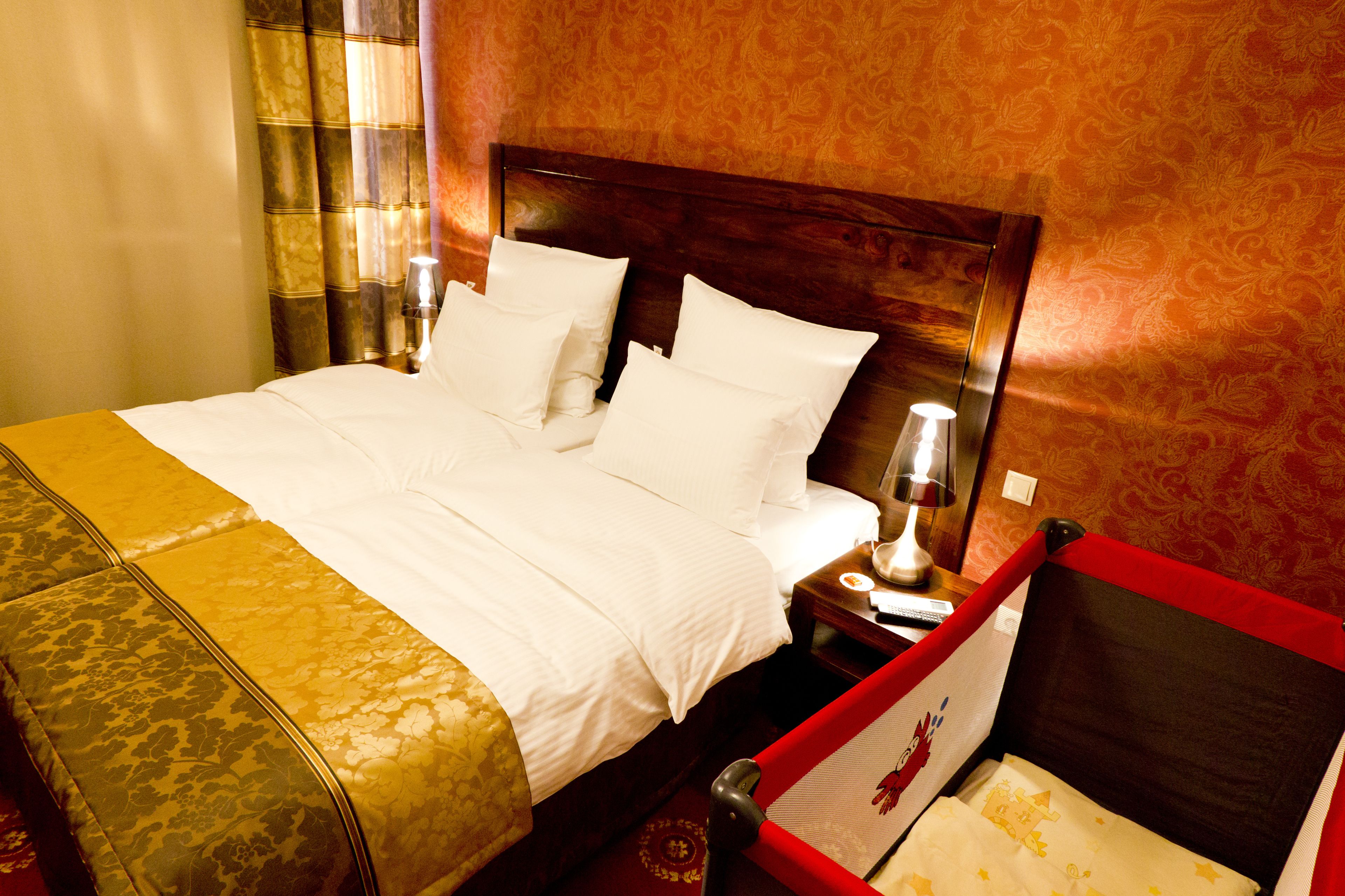 Een hotelkamer met een groot bed, een nachtkastje met een lamp en een rode stoel.