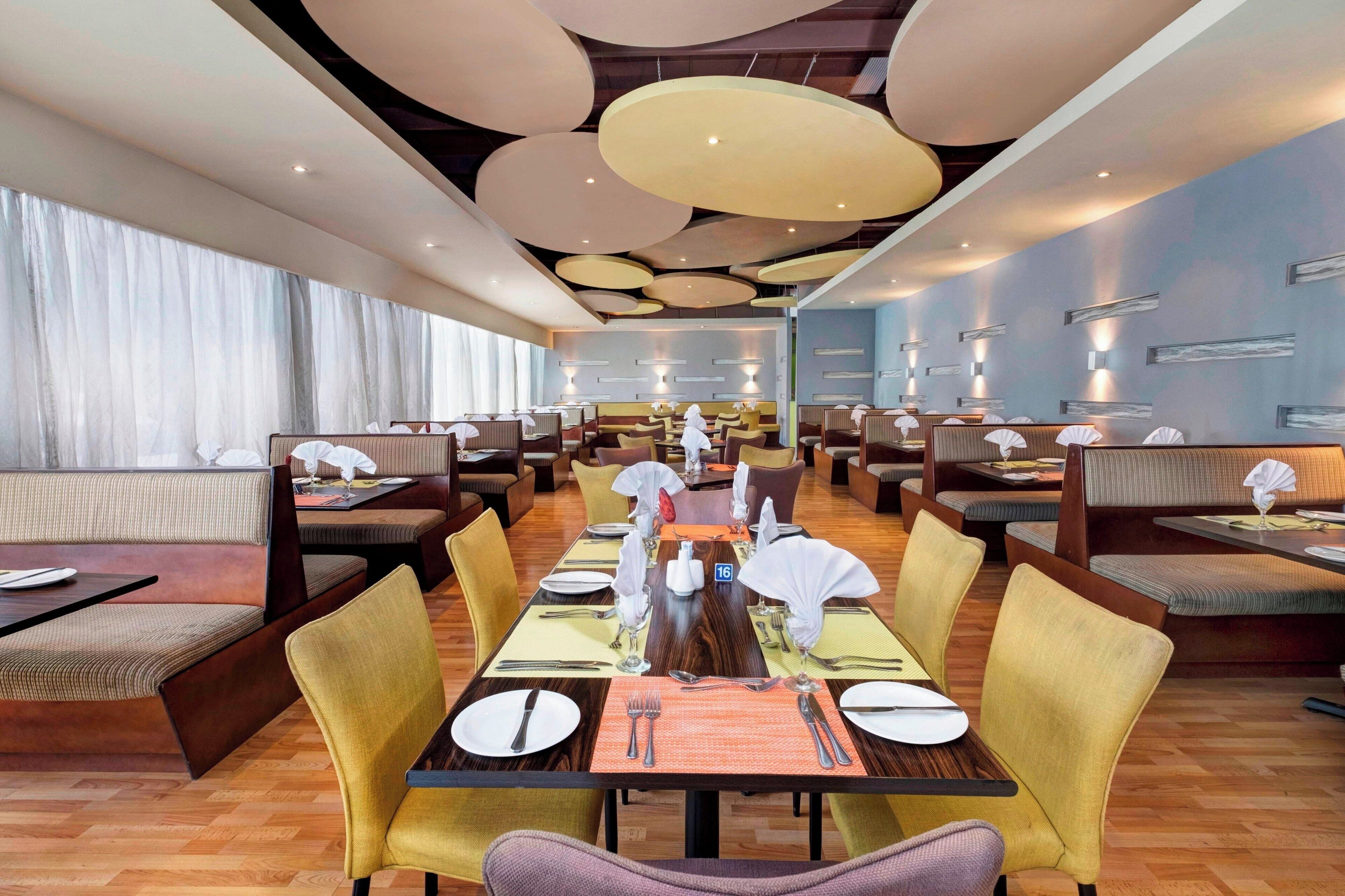 A spacious restaurant with high ceilings, modern lighting, and a variety of seating arrangements including booths and tables.