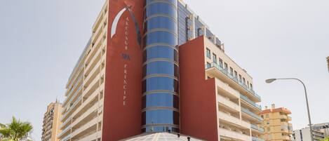 Un edificio de varios pisos con una destacada torre cilíndrica de vidrio, un spa y diversas tiendas en la planta baja.