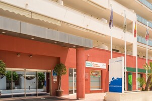 Un edificio con facciata rossa, ingresso in vetro e insegna con la scritta 'Clinica Paseo Girasoles'.