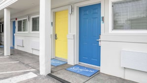 A row of doors with a yellow and a blue door, each with a doormat. - Signature Inn Berkeley (Berkeley)