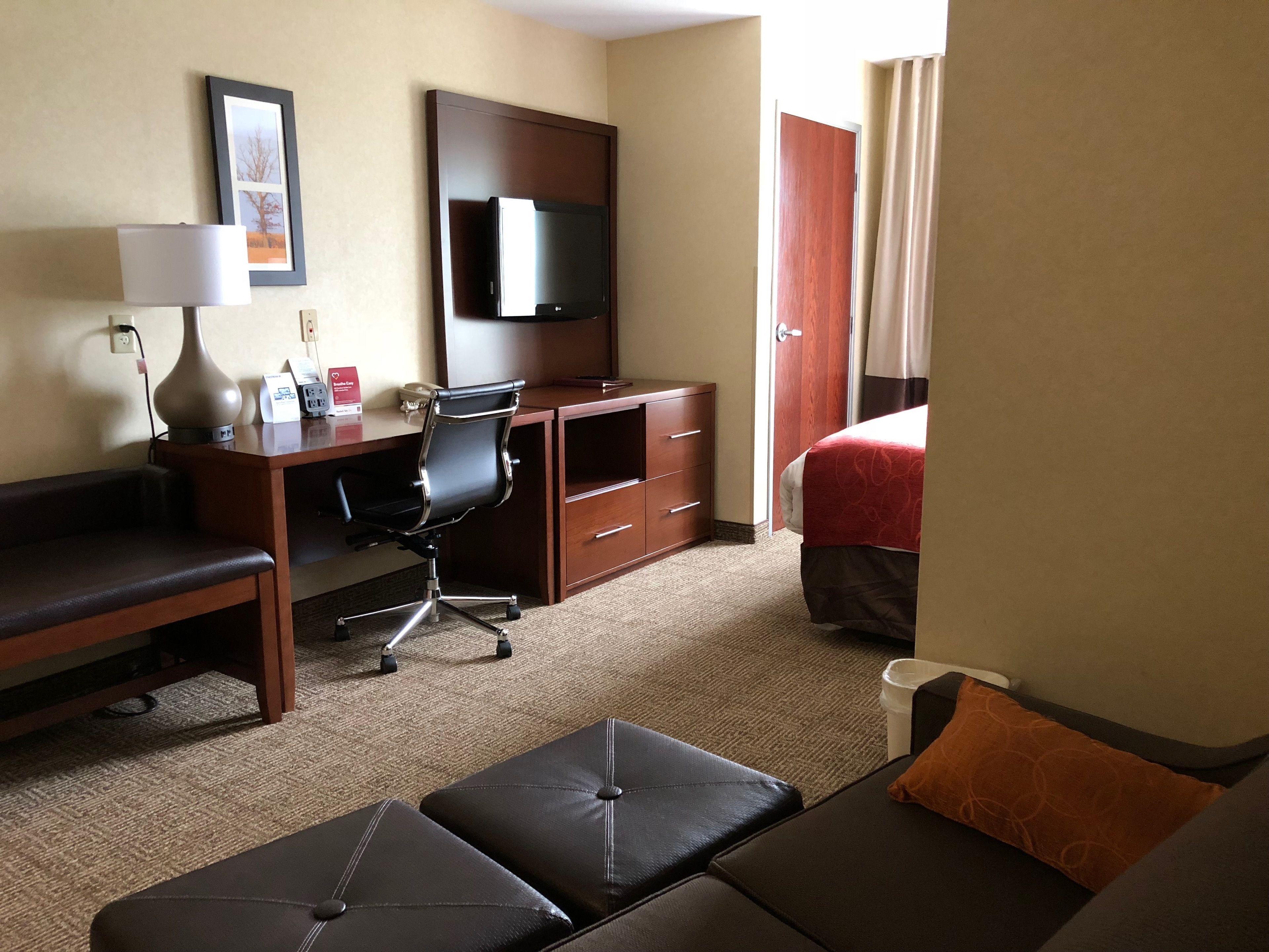 A hotel room with a bed, a desk with a chair, a couch, and a TV.