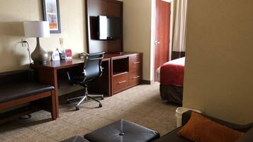 A hotel room with a bed, a desk with a chair, a couch, and a TV.