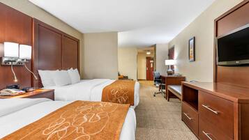 Une chambre d’hôtel avec deux lits, un bureau, une télévision et une salle de bain à l’arrière-plan.