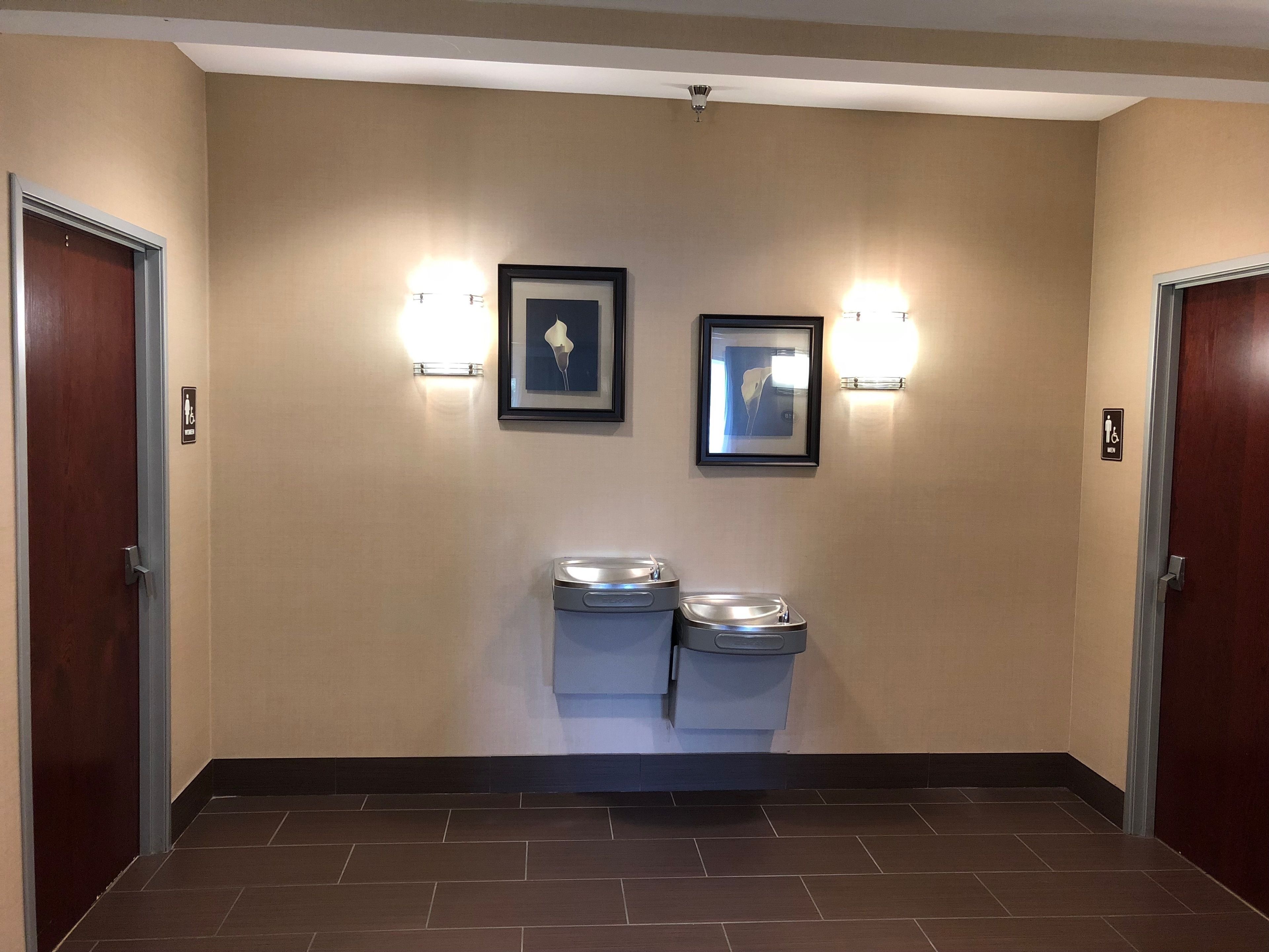 A hallway with two doors, a trash bin, and two wall-mounted light fixtures.