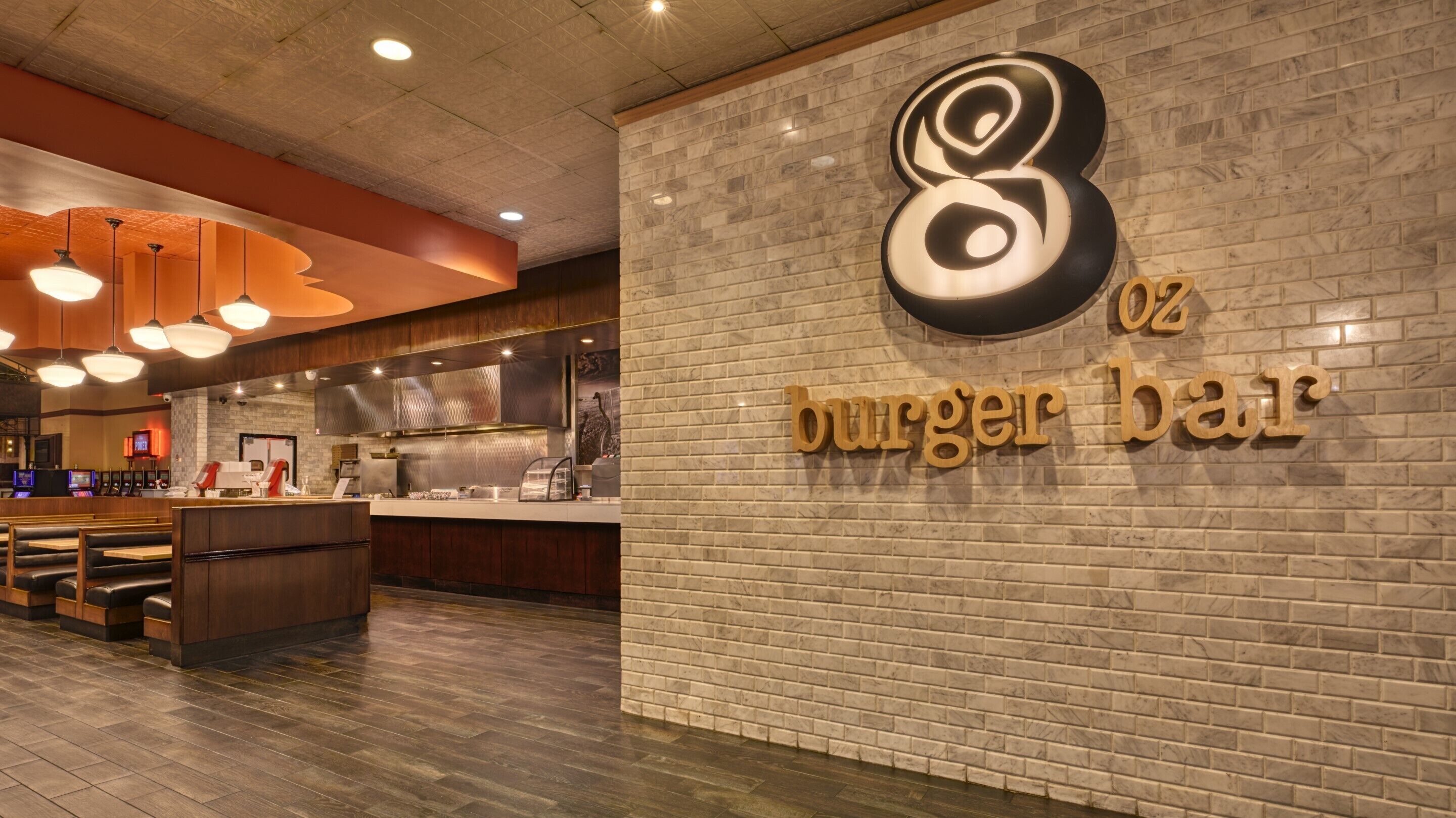 A restaurant interior with a brick wall and a sign reading "8 oz burger bar".