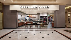 Un Starbucks Coffee amb un mostrador, zona de seients i exposició de begudes.