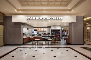Un café Starbucks avec un comptoir, un espace pour s’asseoir et un présentoir pour les boissons.