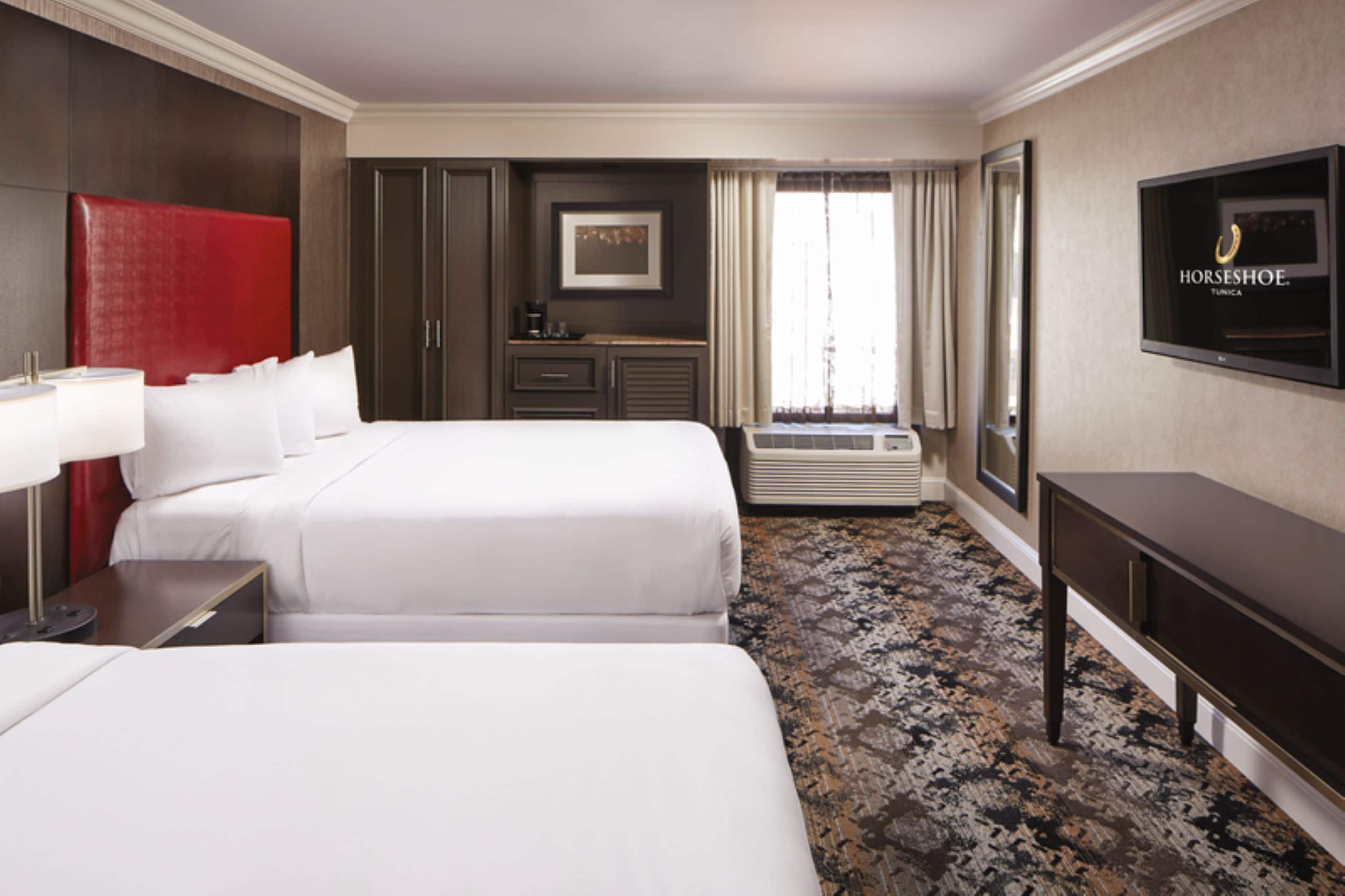 Une chambre d’hôtel avec deux lits, une télévision, un bureau et une armoire.