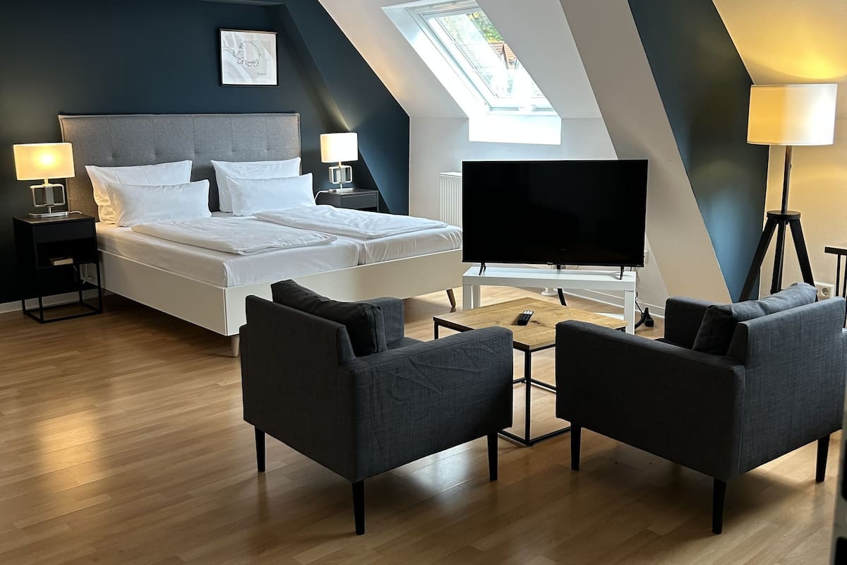 A modern bedroom with a bed, two bedside tables, a TV, and a ceiling fan.