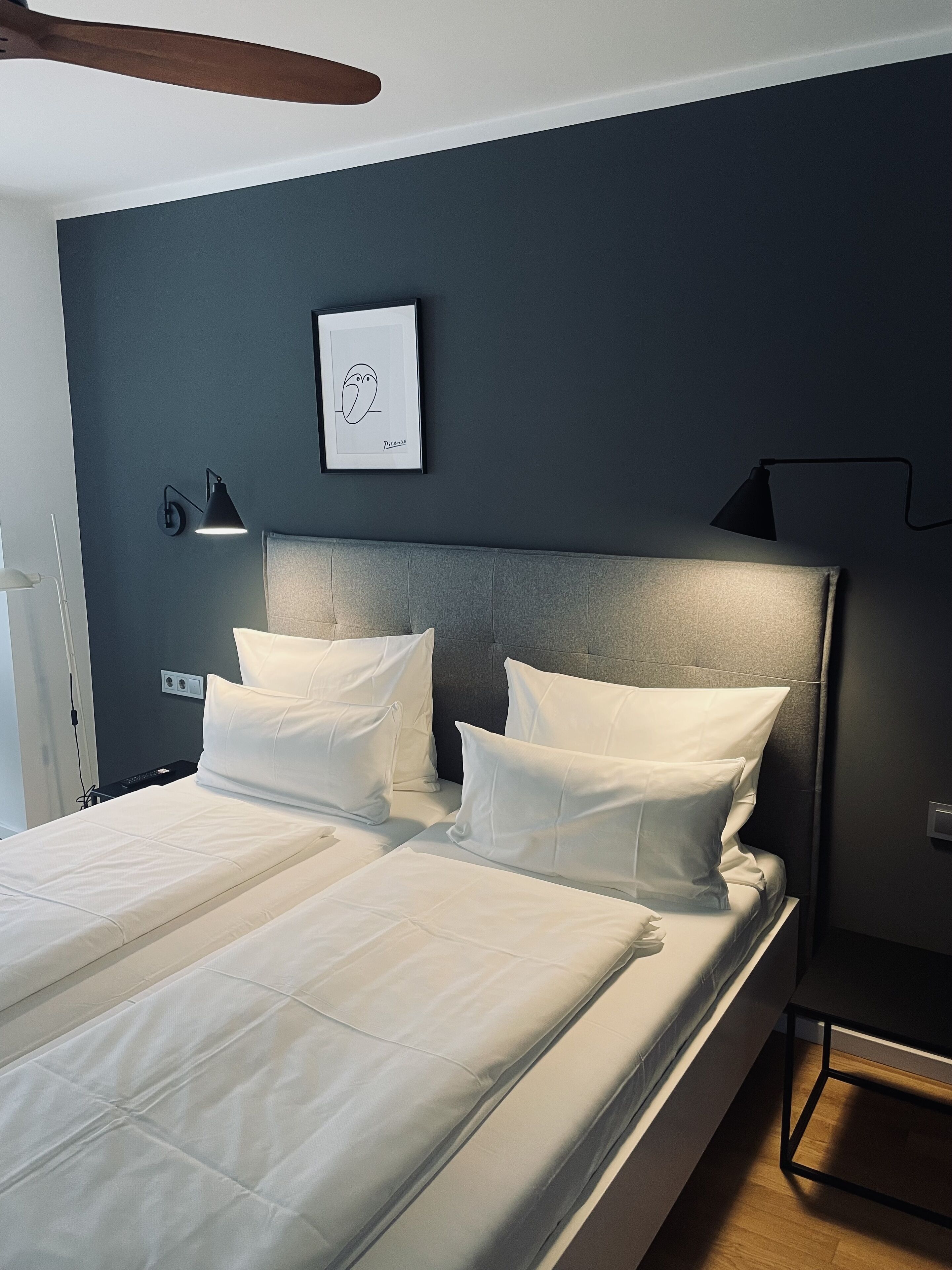 Een moderne slaapkamer met een groot bed, twee bedlampen, een lijst met een kunstwerk en een houten vloer.