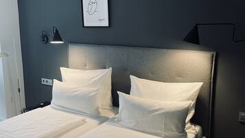 Een moderne slaapkamer met een groot bed, twee bedlampen, een lijst met een kunstwerk en een houten vloer.