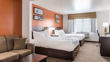 Una habitación de hotel con dos camas, un sofá, un escritorio y una lámpara.