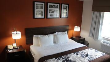 A hotel room with a large bed, two bedside tables with lamps, a wall-mounted telephone, and framed pictures above the bed.