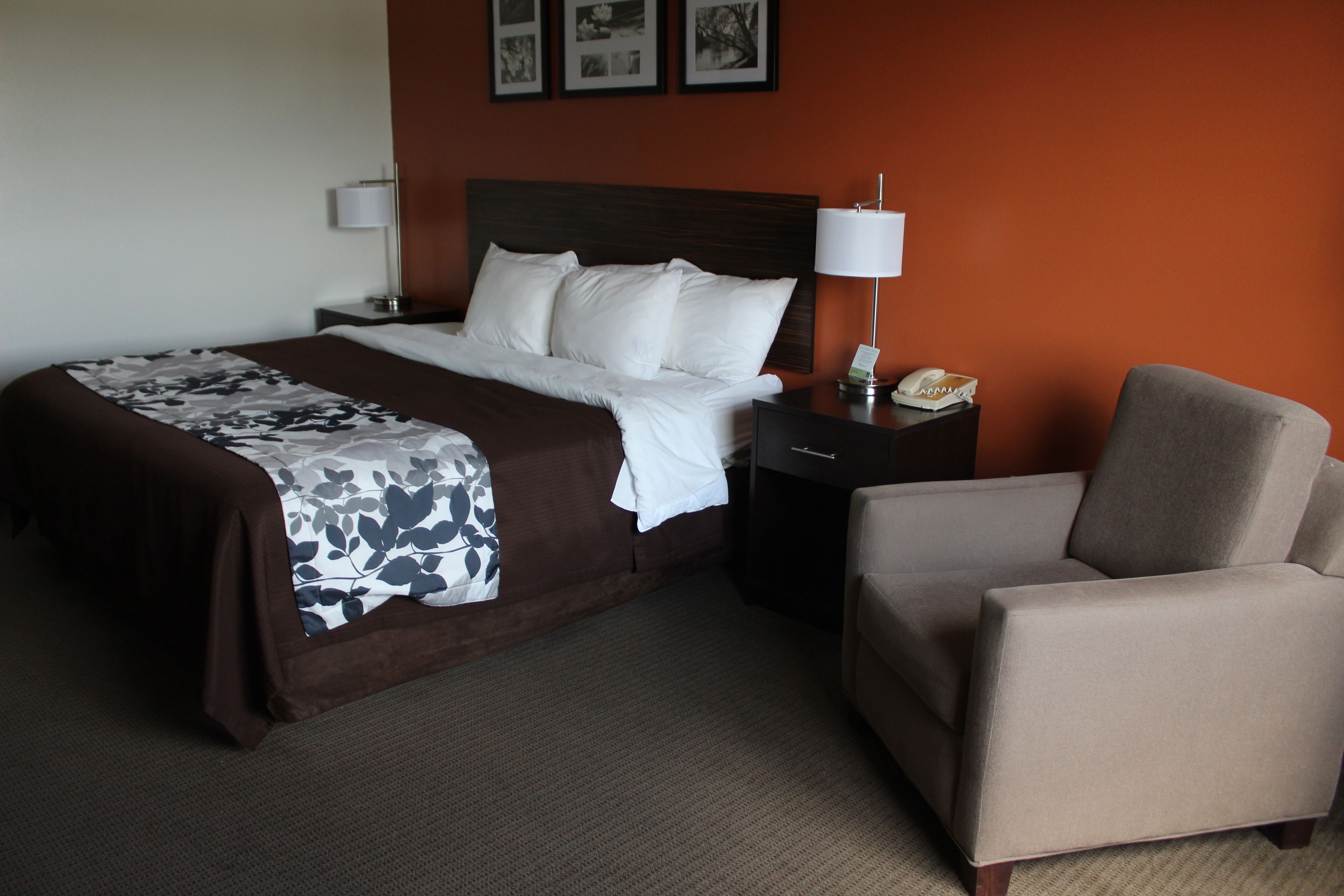 A hotel room with a bed, a nightstand, a lamp, and a chair.