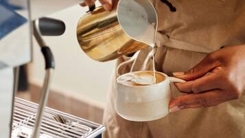 En person häller mjölk i en kopp kaffe.