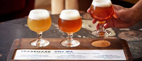 Three glasses of beer on a wooden tray with a label.
