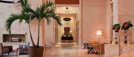 A spacious lobby with a large potted palm tree, a reception desk, and a staircase.