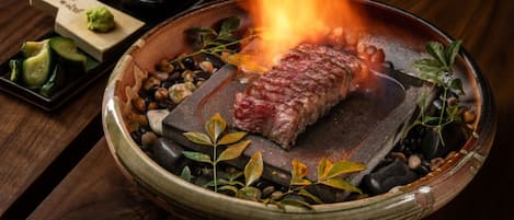 Un filete asado sobre fuego vivo, rodeado de hierbas y especias.