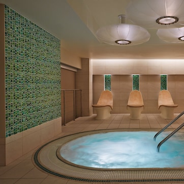 A spa area with a hot tub, tiled walls, and three wooden benches.